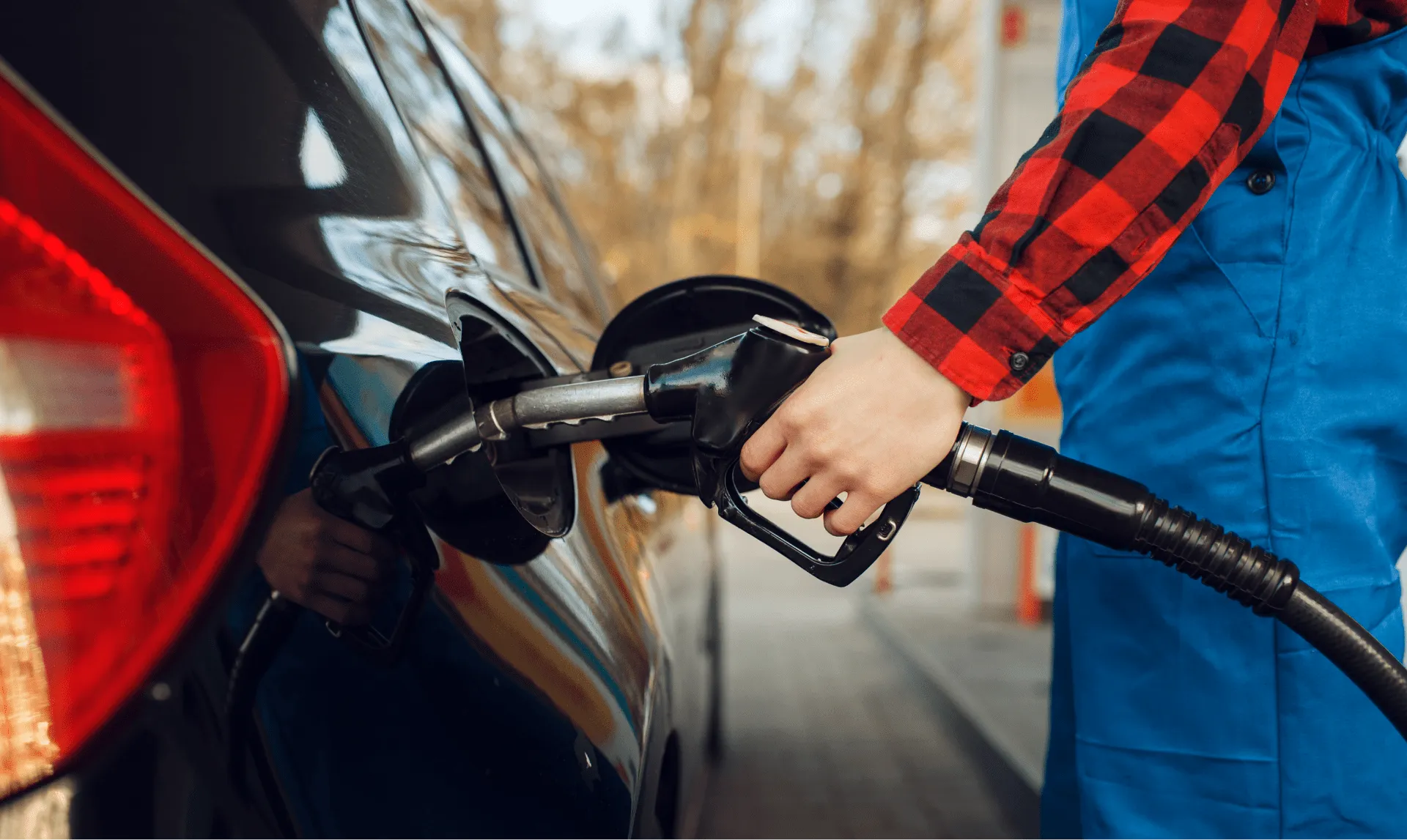 Close-up of a person refuelling a black car at a Gull New Zealand petrol station