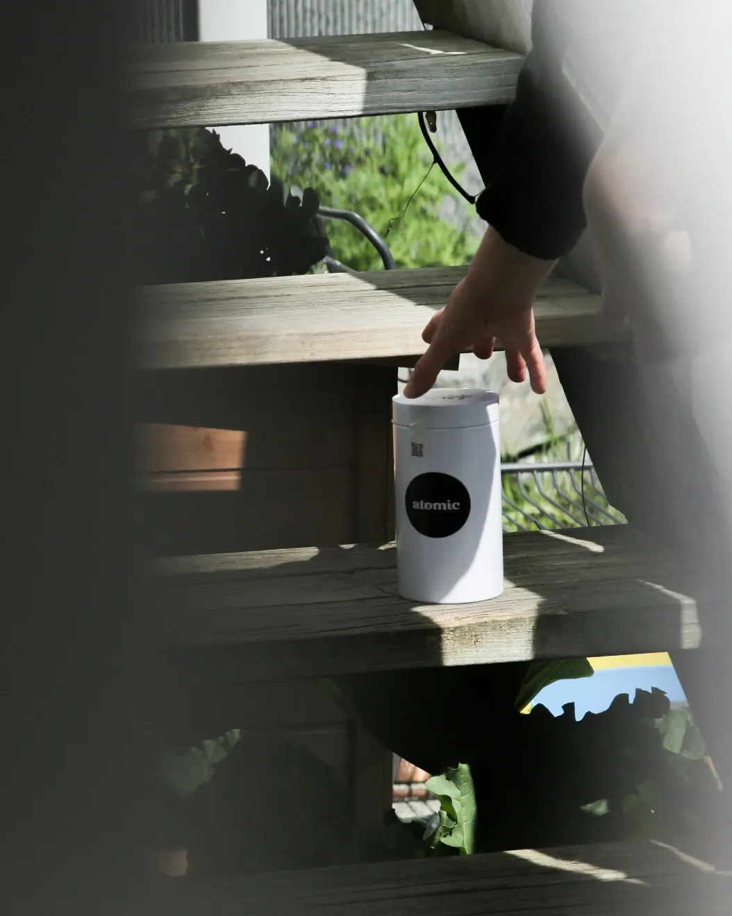 Customer collecting a reusable Atomic coffee canister left on the garden steps