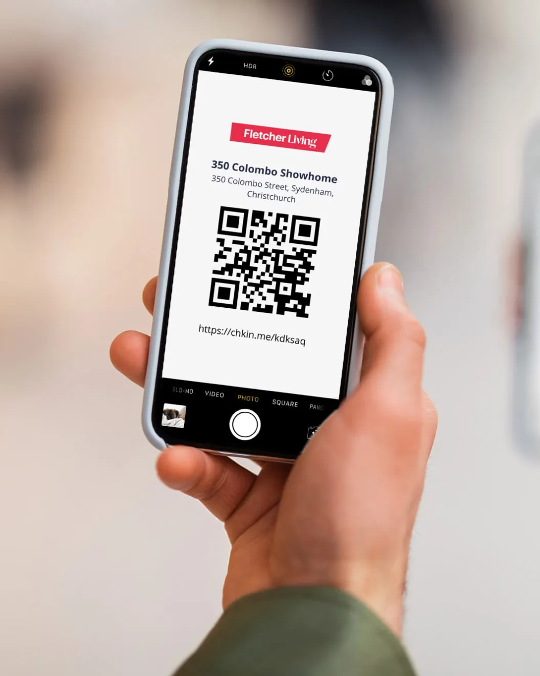 Hand holding a phone scanning the Fletcher Living QR check-in poster at the 350 Colombo showhome