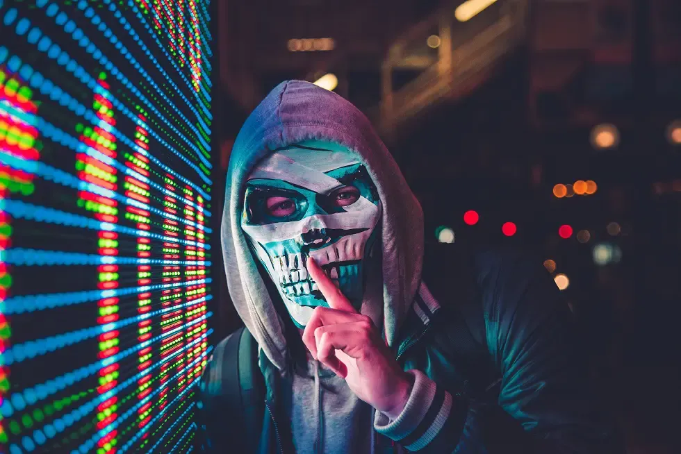 A hooded hacker silhouetted against a glowing crypto-themed digital background