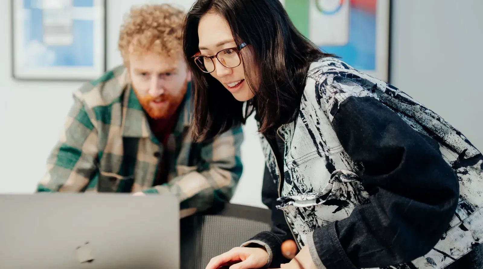 Two Putti team members leaning over a laptop together, working through an early version of a product