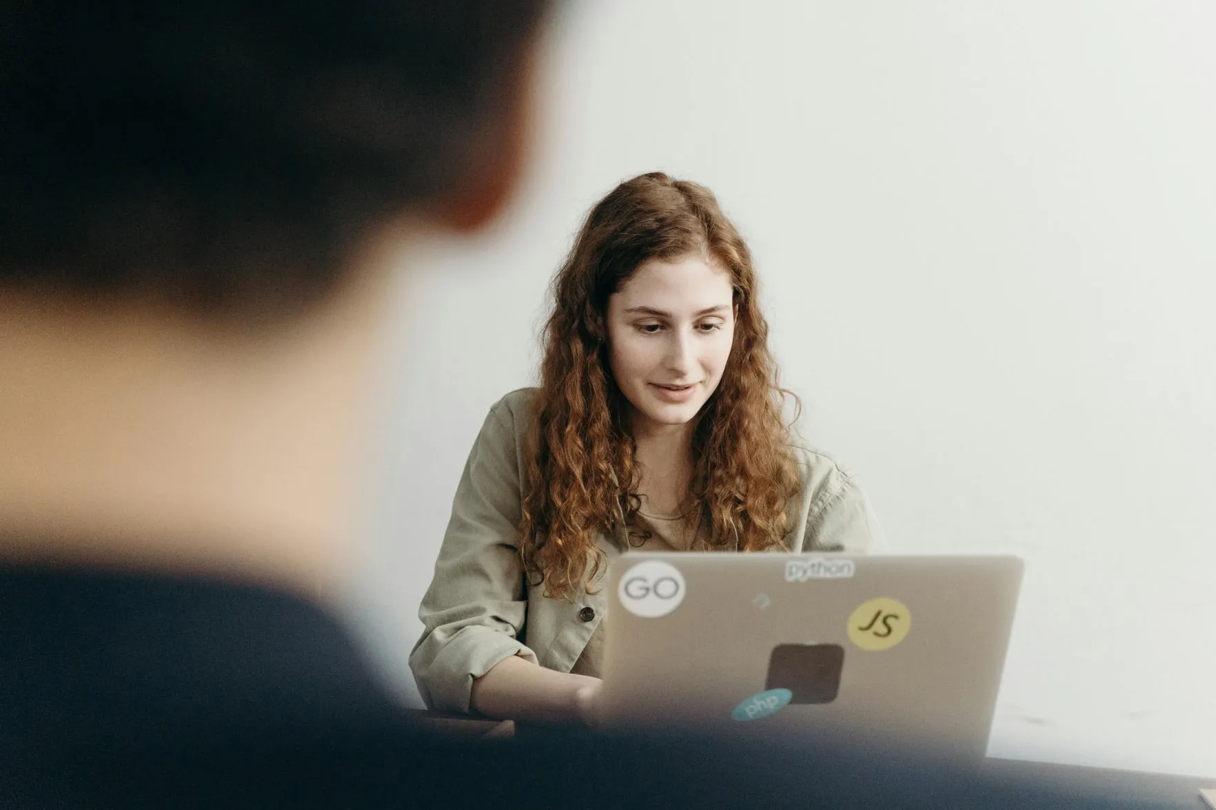 A software developer working on a laptop covered in coding stickers, weighing SaaS and custom build options